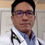 Clinical Research Nurse, Greg Wang in a blue shirt and white lab coat